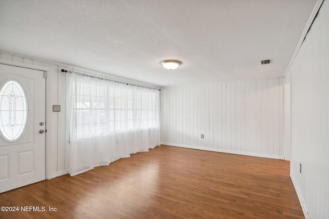 entrance foyer featuring hardwood / wood-style flooring, a textured ceiling, and wooden walls