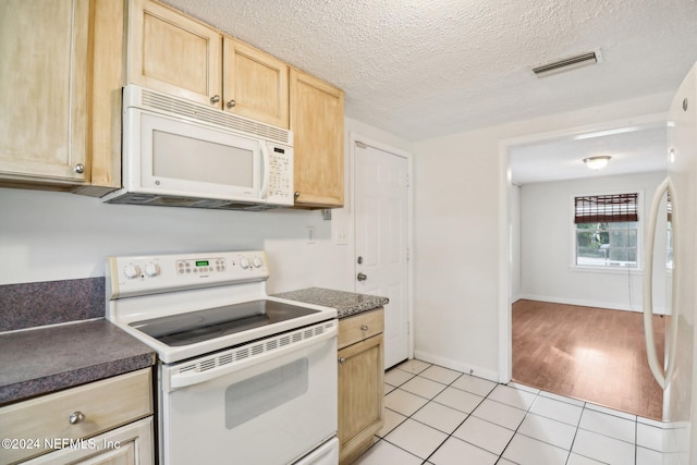 kitchen with light brown cabinetry, white appliances, a textured ceiling, and light hardwood / wood-style floors