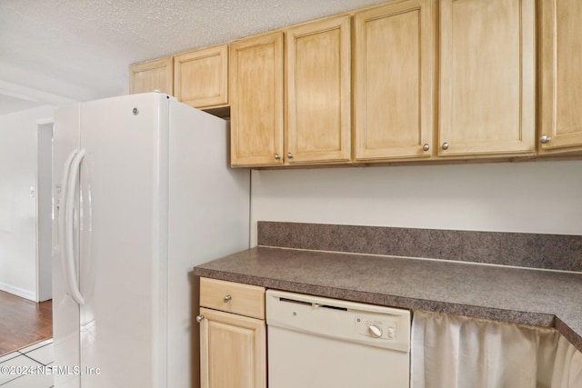 kitchen featuring light brown cabinetry, white appliances, a textured ceiling, and hardwood / wood-style flooring