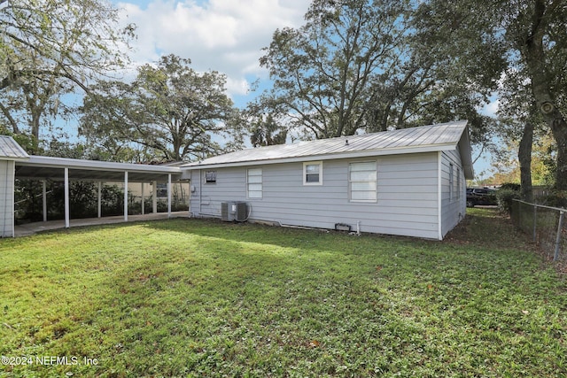 back of house with central AC unit and a lawn