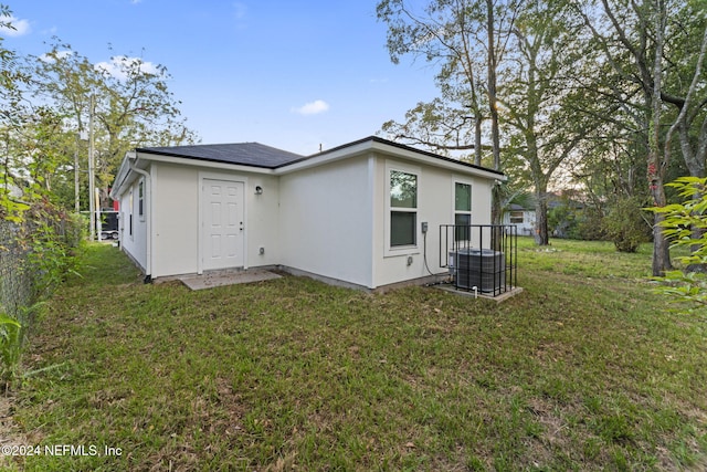 back of house featuring a yard and central AC unit