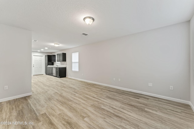 unfurnished living room with a textured ceiling and light wood-type flooring