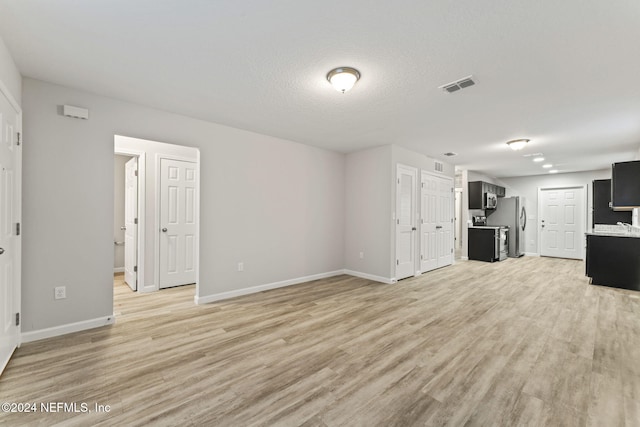 unfurnished living room featuring light hardwood / wood-style flooring and a textured ceiling