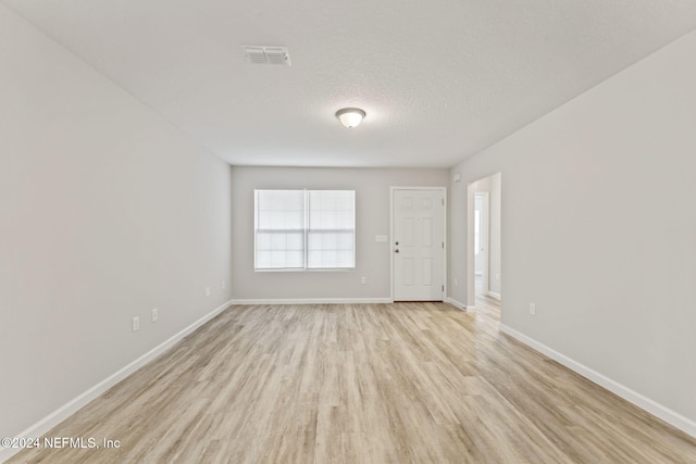 unfurnished room featuring light hardwood / wood-style flooring and a textured ceiling