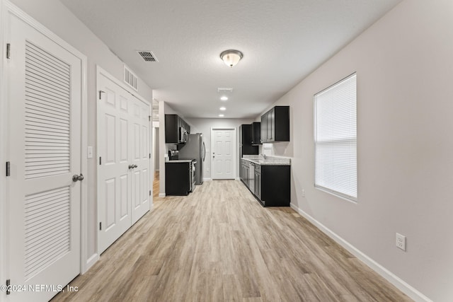 hallway featuring light hardwood / wood-style flooring and a textured ceiling