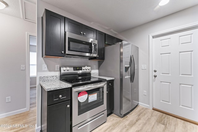 kitchen with light stone counters, stainless steel appliances, and light wood-type flooring