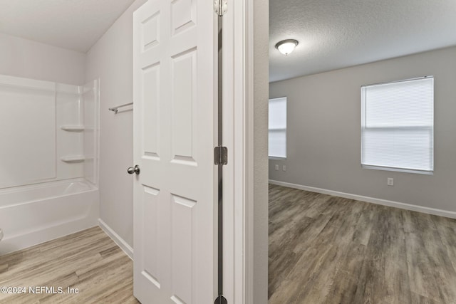 bathroom featuring hardwood / wood-style floors, a textured ceiling, and shower / bathtub combination