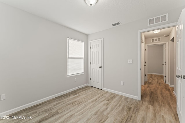 unfurnished bedroom featuring light hardwood / wood-style flooring and a closet