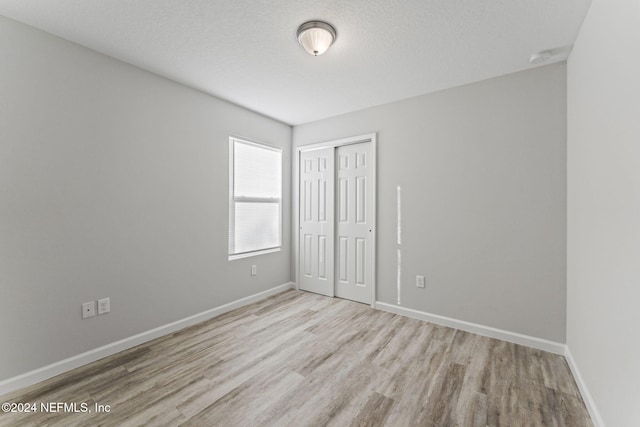 unfurnished room featuring light hardwood / wood-style flooring and a textured ceiling