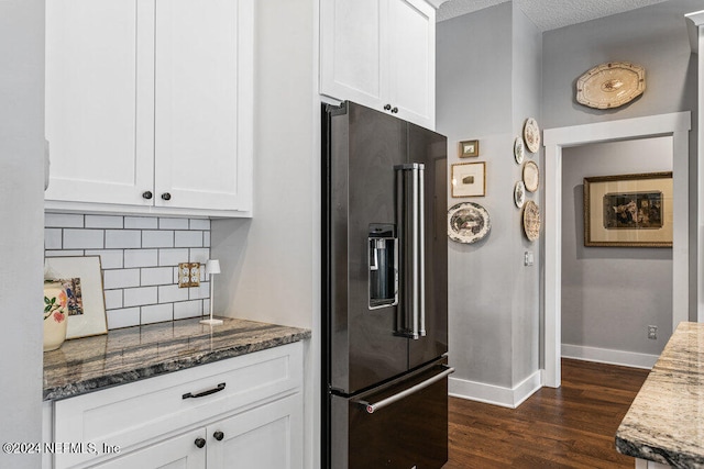 kitchen with a textured ceiling, dark stone counters, high quality fridge, white cabinets, and dark hardwood / wood-style floors