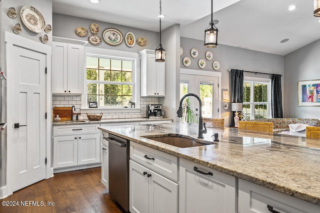 kitchen with white cabinets, light stone countertops, stainless steel dishwasher, dark wood-type flooring, and sink