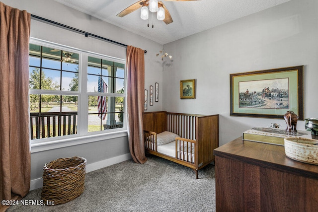 bedroom featuring a nursery area, a textured ceiling, carpet, and ceiling fan