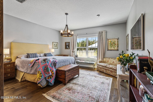 bedroom featuring an inviting chandelier, dark hardwood / wood-style floors, and a textured ceiling