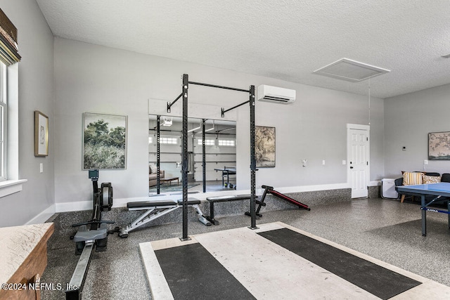 exercise room featuring a textured ceiling and a wall unit AC