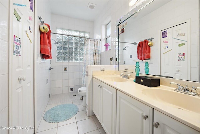 bathroom with tile patterned floors, toilet, vanity, curtained shower, and tile walls