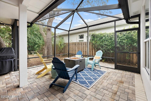 view of patio featuring an outdoor fire pit, grilling area, and glass enclosure