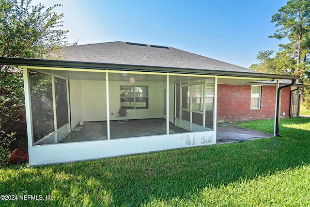 back of house featuring a yard, a patio, and a sunroom