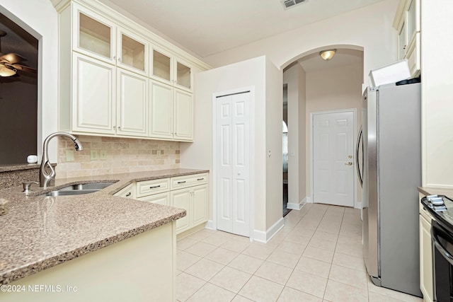 kitchen featuring tasteful backsplash, sink, stainless steel fridge, light stone counters, and light tile patterned floors