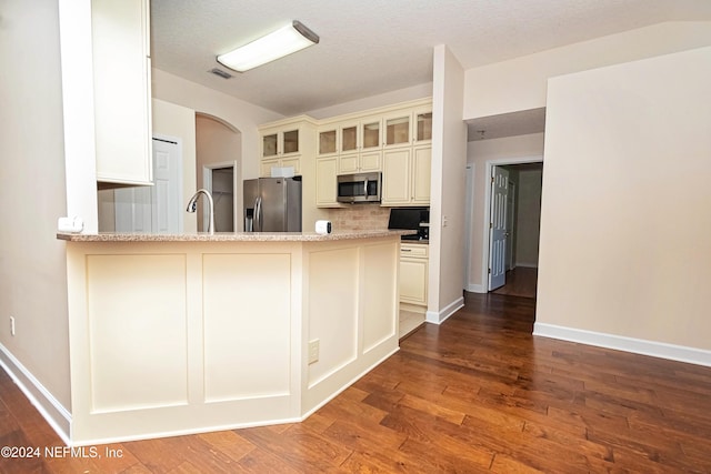 kitchen featuring light stone countertops, dark wood-type flooring, appliances with stainless steel finishes, and a textured ceiling