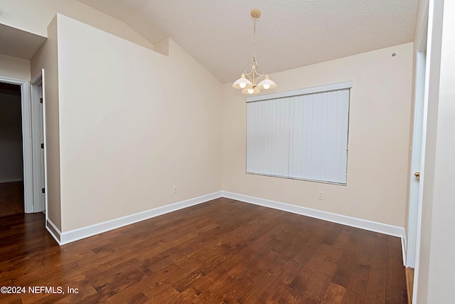 empty room featuring a notable chandelier, a textured ceiling, lofted ceiling, and dark hardwood / wood-style floors