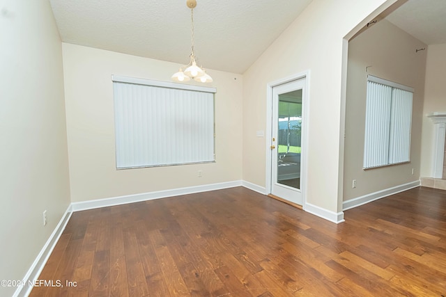 unfurnished dining area with lofted ceiling, a textured ceiling, a notable chandelier, and wood-type flooring