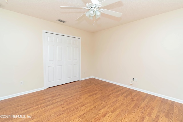 unfurnished bedroom featuring a closet, light hardwood / wood-style floors, a textured ceiling, and ceiling fan