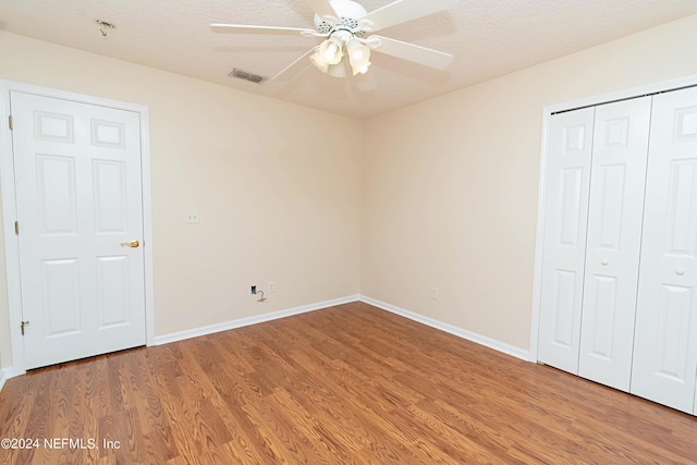 unfurnished bedroom with a closet, ceiling fan, wood-type flooring, and a textured ceiling