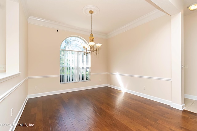 empty room with a notable chandelier, hardwood / wood-style floors, and crown molding