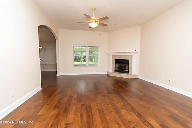 unfurnished living room featuring dark wood-type flooring, ceiling fan, and a tile fireplace