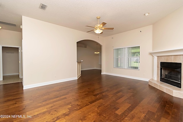 unfurnished living room featuring dark wood-type flooring, ceiling fan, a textured ceiling, and a fireplace