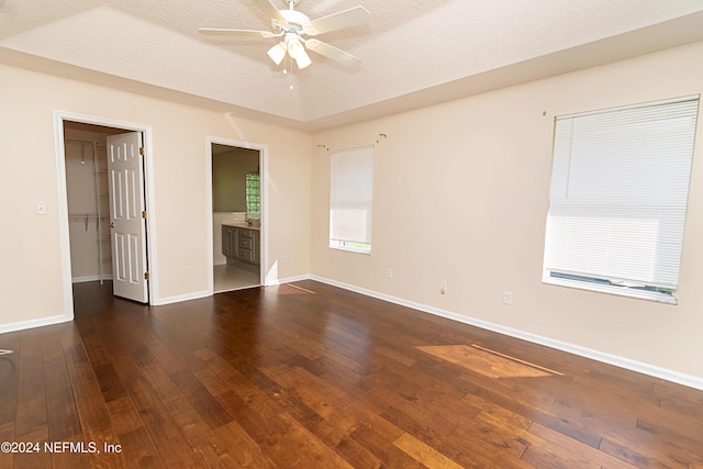 empty room with a textured ceiling, dark wood-type flooring, and ceiling fan