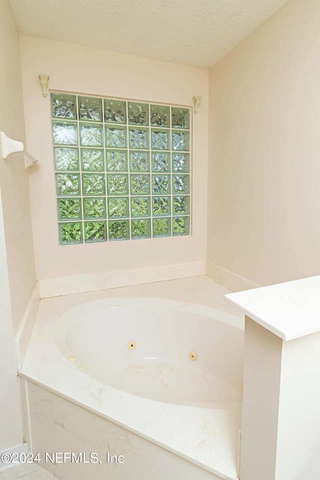 bathroom with a bathing tub, a textured ceiling, and plenty of natural light