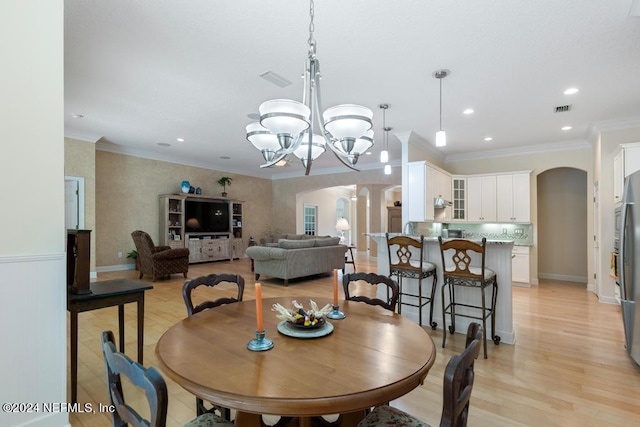 dining room featuring an inviting chandelier, crown molding, and light wood-type flooring