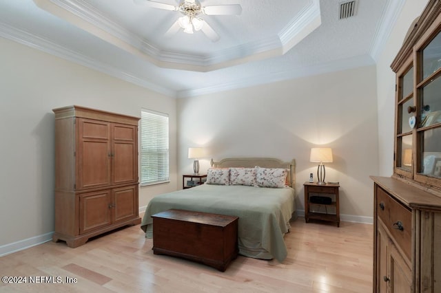 bedroom featuring ceiling fan, crown molding, light hardwood / wood-style flooring, and a raised ceiling