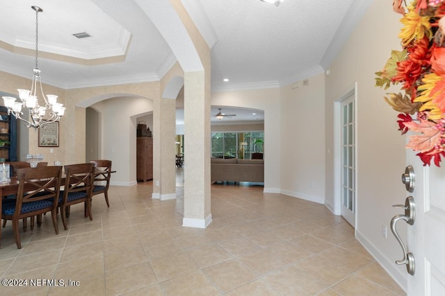 tiled foyer entrance with ornamental molding and ceiling fan with notable chandelier