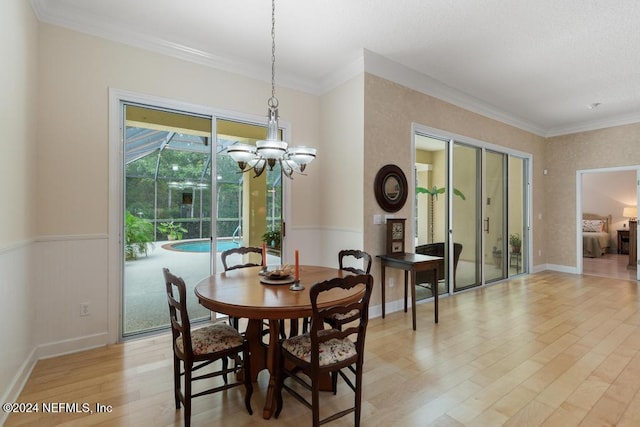 dining area featuring a notable chandelier, ornamental molding, and light hardwood / wood-style flooring