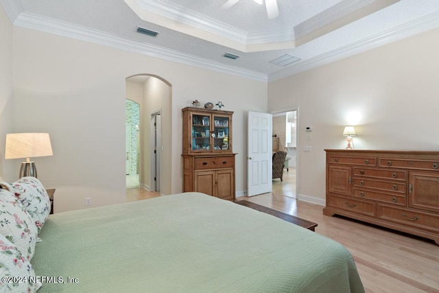 bedroom with crown molding, light hardwood / wood-style flooring, a raised ceiling, and ceiling fan