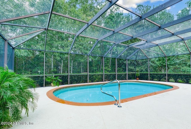 view of pool with a patio area and glass enclosure