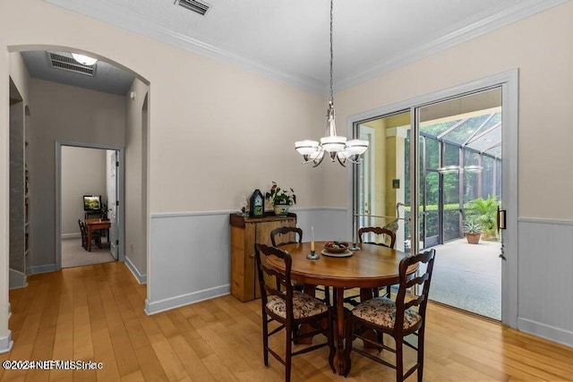 dining space featuring an inviting chandelier, crown molding, and light wood-type flooring