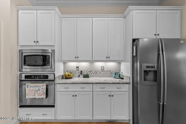 kitchen with appliances with stainless steel finishes, decorative backsplash, white cabinetry, light stone counters, and ornamental molding