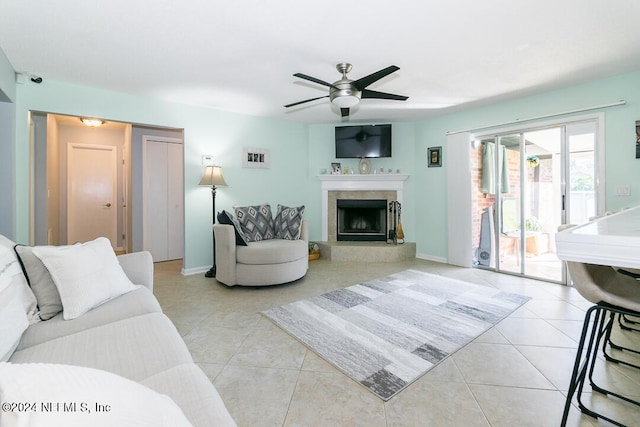 living room with ceiling fan, a fireplace, and light tile patterned floors