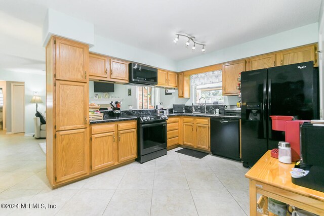 kitchen featuring light tile patterned floors, black appliances, and sink