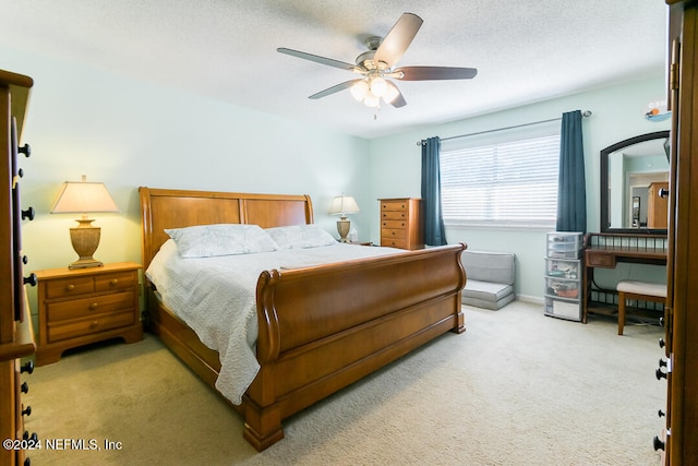 bedroom featuring a textured ceiling, light colored carpet, and ceiling fan