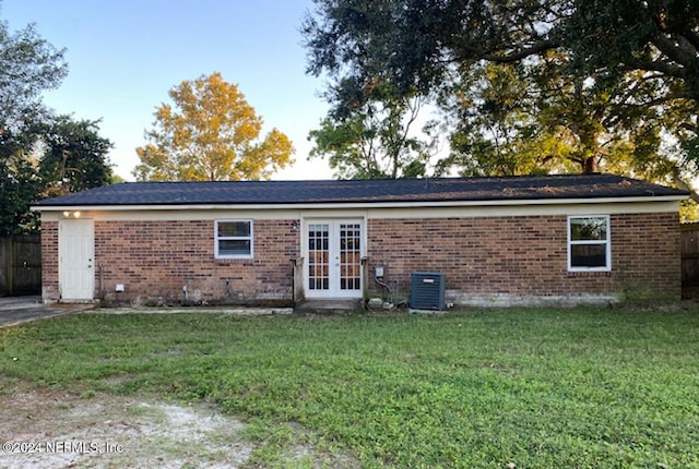 rear view of house featuring french doors, a yard, and central air condition unit