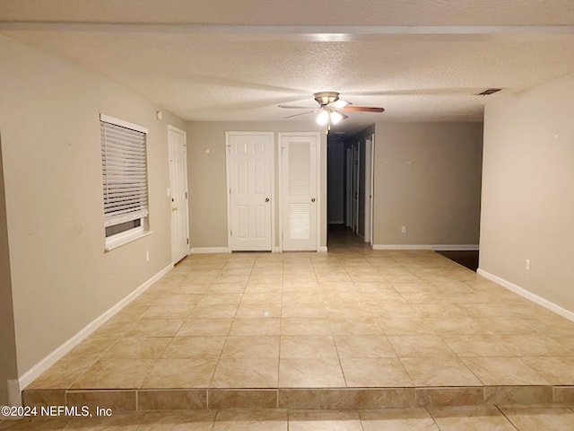 spare room featuring ceiling fan, a textured ceiling, and light tile patterned floors