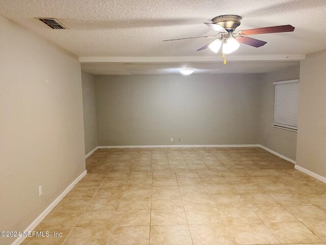 tiled spare room featuring a textured ceiling and ceiling fan