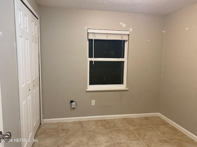 laundry room featuring light tile patterned flooring and a textured ceiling