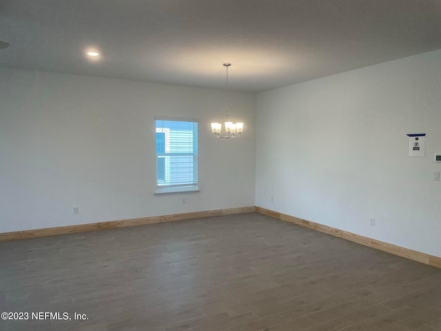 spare room with hardwood / wood-style flooring and an inviting chandelier