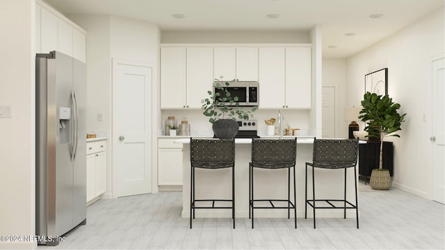 kitchen with stainless steel appliances, an island with sink, a kitchen breakfast bar, and white cabinets