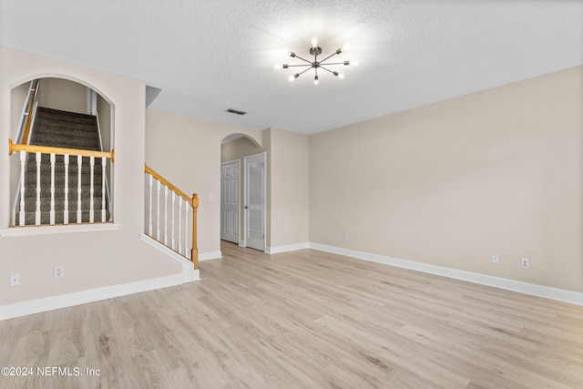 empty room featuring a textured ceiling and light hardwood / wood-style floors